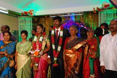 a group of people standing next to each other in front of a stage decorated with flowers and garlands