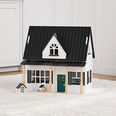 a white house with black roof and windows on carpeted floor next to cabinet doors