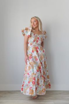 Introducing our smocked puff sleeve flower printed maxi dress! With a square neckline, puff sleeves, and a smocked top, it offers both style and comfort. Includes hidden side seam pockets and a tiered skirt. Perfect for any occasion, this dress is a must-have for your wardrobe. puff sleeves floral print tiered maxi length colorful lined pockets true to size 100% cotton model is wearing a small Square Neck Ruched Maxi Dress For Brunch, Square Neck Maxi Dress With Smocked Back For Brunch, Square Neck Midi Dress With Gathered Sleeves For Vacation, Summer Square Neck Smock Maxi Dress, Floral Print Puff Sleeve Maxi Dress For Brunch, Puff Sleeve Maxi Dress With Floral Print For Brunch, Casual Maxi Dress With Ruffle Hem And Square Neck, Casual Floral Print Maxi Dress With Puff Sleeves, White Smocked Dress With Floral Print And Square Neck