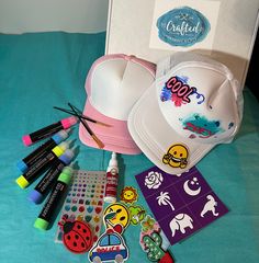 the hat is next to markers, pens, and other items for making crafts on a bed