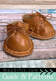 a pair of brown leather baby moccale shoes on top of a wooden floor