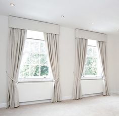 an empty room with two windows and curtains