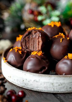 chocolate covered orange peels in a bowl on top of a table with an orange flower