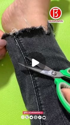 someone using scissors to cut the jeans