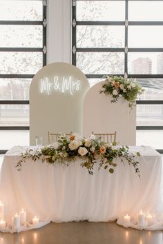 a table with candles and flowers on it in front of a large sign that says mr & mrs