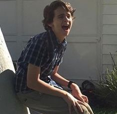 a young man sitting on top of a cement bench in front of a garage door