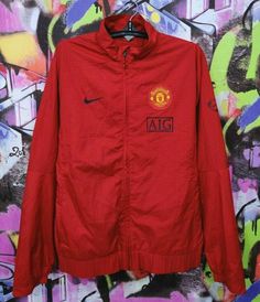 a red manchester united jacket hanging on a wall with graffiti in the backround