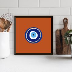 an orange and blue framed print with the eyeball logo on it next to some kitchen utensils