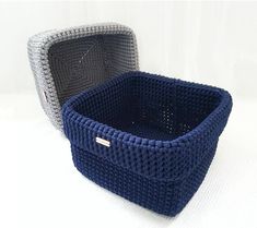 two knitted baskets sitting next to each other on a white tablecloth covered surface