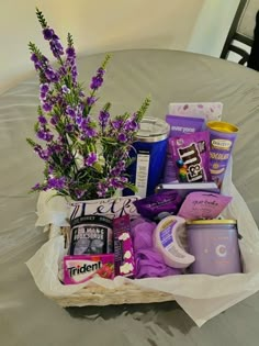 a basket filled with lots of different items on top of a bed next to a table