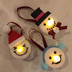 three snowmen with lights on their heads and one is wearing a santa claus hat