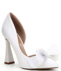 a pair of white shoes with a bow on the heel