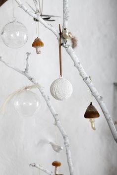 an assortment of ornaments hanging from a tree branch in front of a white stucco wall