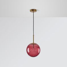 a red glass ball hanging from a brass plated light fixture