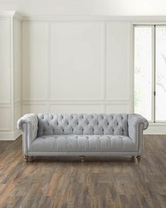 a couch sitting on top of a hard wood floor next to a window in a room