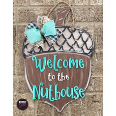 a welcome sign hanging on the side of a brick wall that says, welcome to the nuthouse