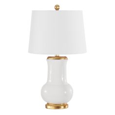 a white lamp with a gold base and a white shade on the top, against a white background