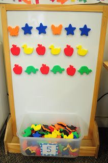 a white board with colorful magnets on it in a playroom filled with toys