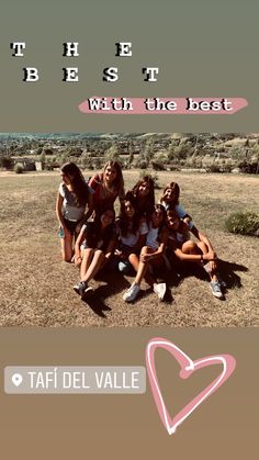 a group of young women sitting on top of a grass covered field next to a heart