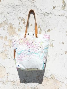 Original design hand painted tote bag handcrafted with white water-resistant upcycled canvas.  Features a unique paint splatter design all around.   I use non-toxic paint which is sealed for protection and it will not rub off or transfer to clothes. This bag is lined and has an open top which secures with two snaps.  Large interior tropical print fabric pocket to store easy to reach items.  As an option, switch the bag inside out to wear it reversed as an all white tote exposing the pocket to the exterior side. Natural leather straps are reinforced and comfortably fit over shoulder. A unique carry all, generously sized for everyday essentials. All handbags are shipped in a drawstring dust bag. Approximate Dimensions:   Height (not including handles) 36.5 cm (14.4 in) Width 26.5 cm (10.4 in Splatter Paint Canvas, Tropical Fabric Prints, Tote Bag Art, Unique Handbag, Red Leather Bag, Painted Tote, Paint Canvas, Splatter Paint, Bag Art