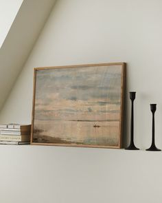 a painting on the wall next to two black candles and a book shelf with books