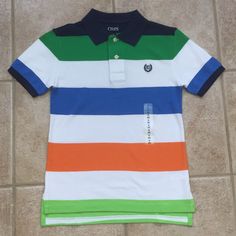 Chaps Boys Wide Striped Polo Shirt Short Sleeve Polo Shirt Sporting Navy, Green, White, Blue, Orange And Lime Stripes, Ribbed Navy Collar And Cuffs, Two Button Placket, And Tennis Tail, Embroidered Crest On Chest New With Tags Chaps Size: S (8) Colors: Navy, Green, White, Blue, Orange, Lime 100% Cotton New To Poshmark? Use Code Rvalm When You Sign Up And Get $10 Off Your First Order! Fitted Multicolor Tops For School, Playful Collared Blue Tops, Playful Blue Collared Top, Polo Shirt Girl, Polo Shirt Colors, Green Polo Shirts, Boys Stripes, Uniform Shirts, Blue Polo Shirts