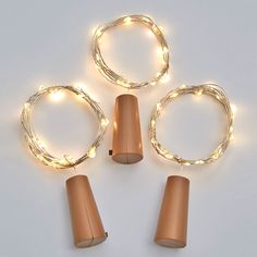 three copper colored lights with white wire around them on a white surface, surrounded by smaller brown lamps