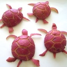 four pink sea turtles sitting on top of a white surface