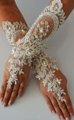 a woman's hands with white lace and flowers on them, both wearing gloves