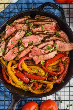 steak and peppers in a skillet with tomatoes