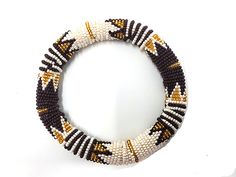 Beautiful beaded authentic bold thick bangle handmade by Zulu women in South Africa. Bangle is handmade using glass beads, yarn and cotton. We directly work with Zulu women to produce and market high-end beaded jewelry based on traditional beading techniques infused with modern aesthetics. Our bangles are created entirely by hand and variations in design may occur. Each piece tells a story. Beaded jewelry is part of the Zulu identity and through our collection, we tell their stories and preserve Handwoven Beaded Bracelets With Round Beads, Traditional Handmade Brown Bangle, Festive Handmade Beaded Bracelets, Traditional White Handwoven Beaded Bracelets, Adjustable Beaded White Bangle, Adjustable White Beaded Bangle, White Handwoven Bracelets, Traditional Handwoven Beaded Bracelets, White Beaded Bangle With Round Beads