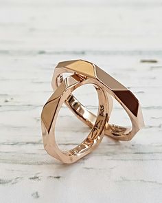 two gold wedding rings sitting on top of each other