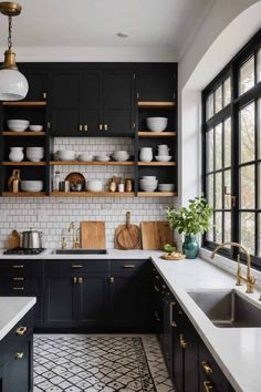 a kitchen with black cabinets, white counter tops and gold pulls on the shelves above the sink