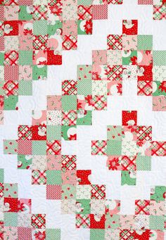 a close up of a quilt made with red, green and white squares