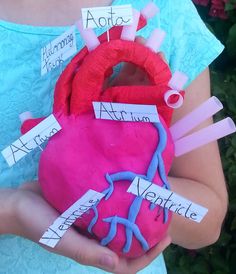 a person holding a pink heart shaped object with writing on it and stickers attached to it