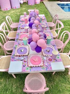 a table set up for a birthday party with pink and purple balloons, plates, napkins and cups