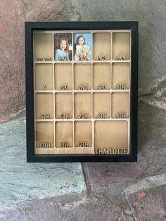 a photo frame with photos on it sitting next to a stone wall in the shape of a calendar