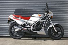 a white and red motorcycle parked in front of a garage door