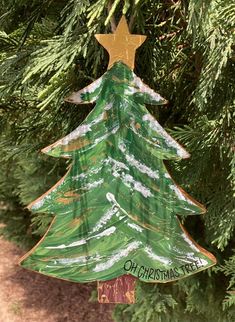 a green christmas tree ornament hanging from a pine tree with a star on top