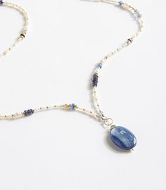 a blue and white beaded necklace with an oval shaped stone hanging from it's side