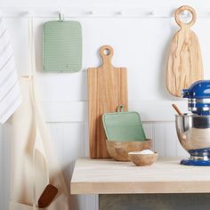 kitchen utensils and wooden cutting boards hang on the wall