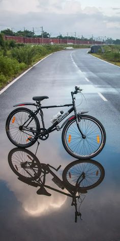 a bike that is sitting on the side of a road with its reflection in the water