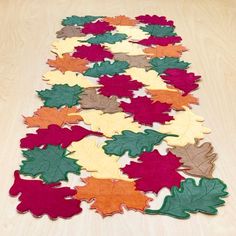 a wooden table topped with lots of different colored leaf shaped rugs on top of it