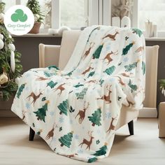 a christmas tree and deer print blanket on a chair in front of a window with holiday decorations