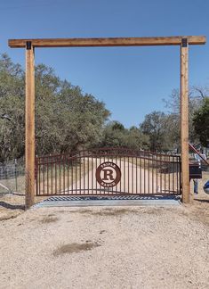 a gated entrance to a dirt lot with trees in the background