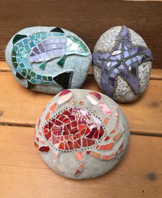 three different colored rocks sitting on top of a wooden table