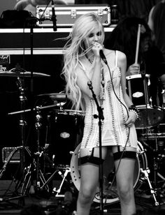 a black and white photo of a woman on stage with a microphone in her hand