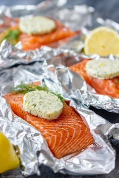 salmon fillets on aluminum foil with lemon wedges