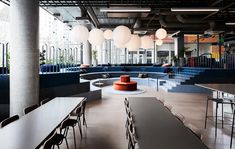 an empty room with tables and chairs in the foreground, lights hanging from the ceiling