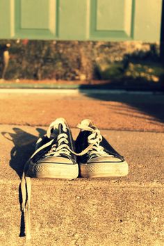 a pair of shoes sitting on the ground in front of a green door with a black shoelace